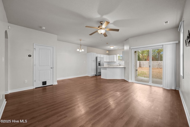 unfurnished living room featuring dark hardwood / wood-style flooring and ceiling fan with notable chandelier