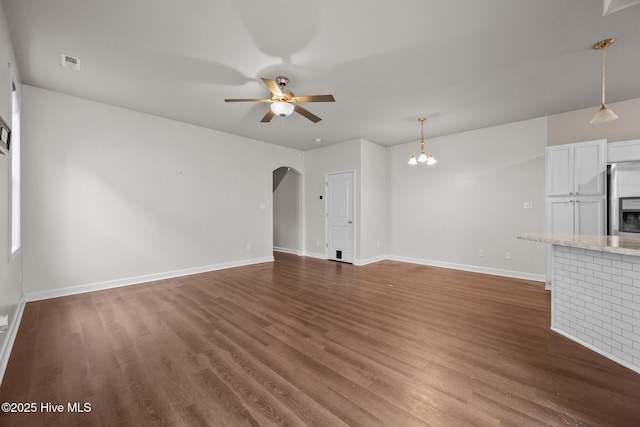 unfurnished living room with ceiling fan with notable chandelier and dark wood-type flooring