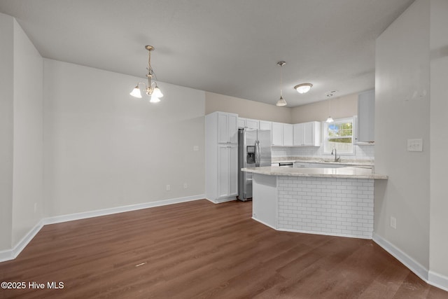 kitchen featuring white cabinets, sink, stainless steel fridge with ice dispenser, decorative backsplash, and kitchen peninsula