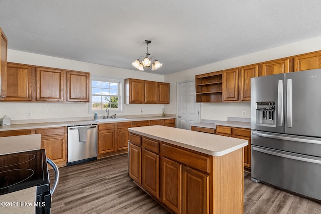 kitchen with a kitchen island, appliances with stainless steel finishes, dark hardwood / wood-style floors, hanging light fixtures, and sink