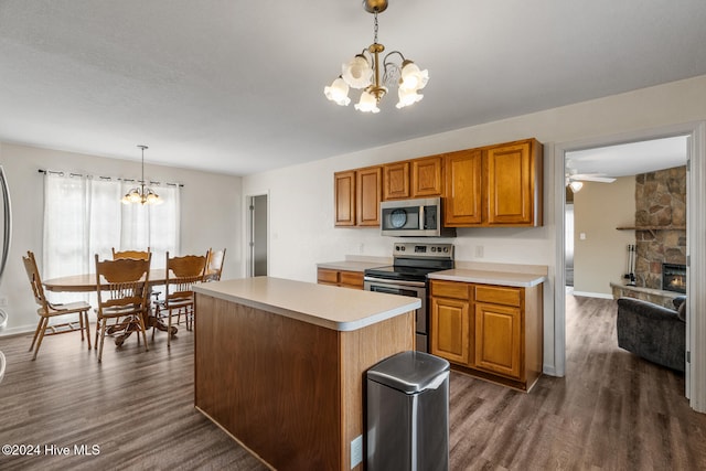 kitchen featuring stainless steel appliances, a fireplace, decorative light fixtures, and dark hardwood / wood-style flooring