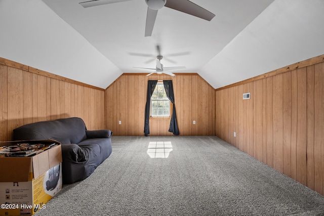 sitting room with wood walls, ceiling fan, carpet flooring, and lofted ceiling