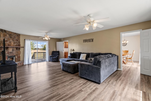 living room featuring a stone fireplace, hardwood / wood-style flooring, and ceiling fan