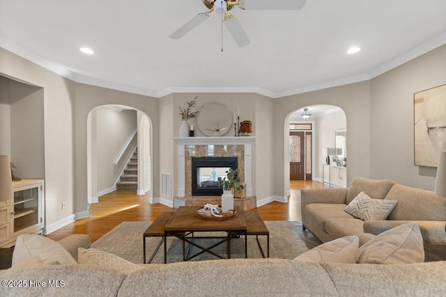 living room featuring crown molding, wood-type flooring, and a tiled fireplace