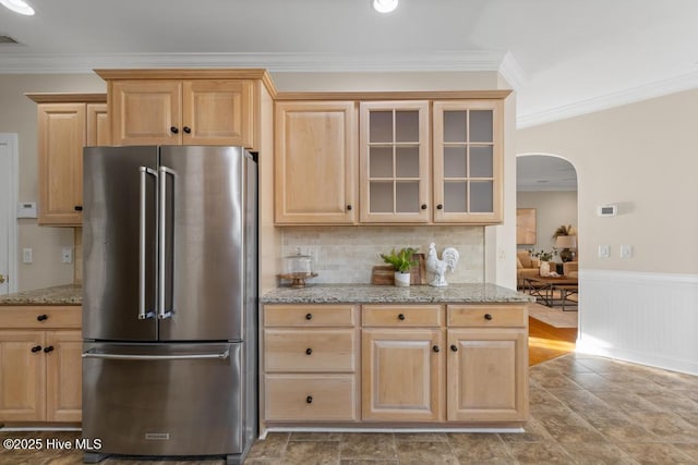 kitchen with freestanding refrigerator, arched walkways, and light brown cabinets