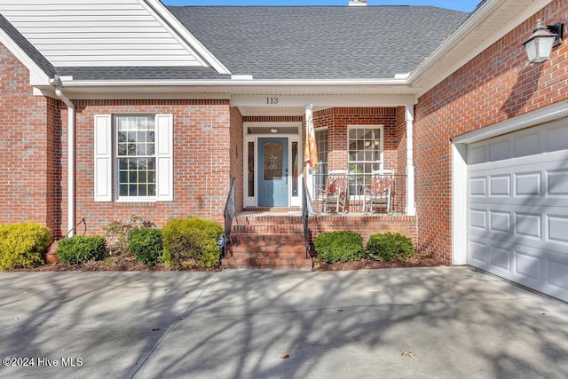doorway to property with brick siding, an attached garage, and roof with shingles
