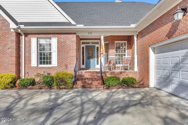 doorway to property featuring a porch and a garage