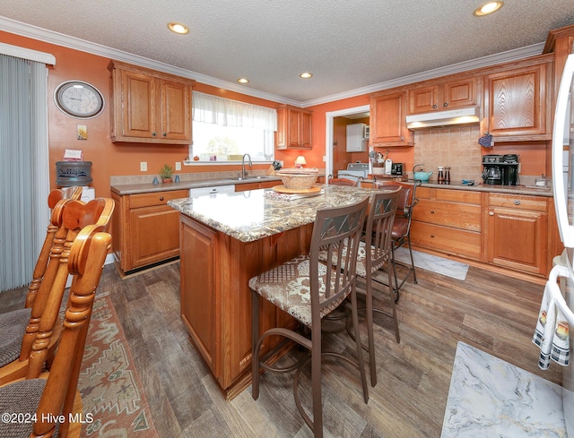 kitchen featuring sink, dark hardwood / wood-style flooring, a center island, crown molding, and a textured ceiling