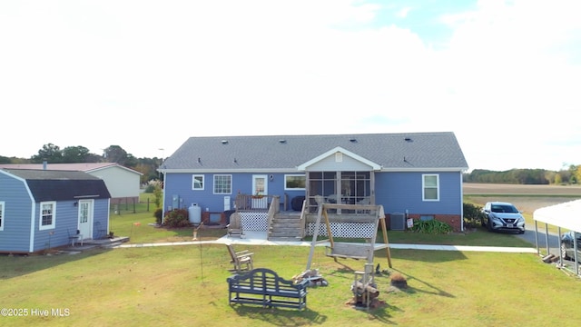 rear view of property featuring a lawn, central air condition unit, and a storage unit