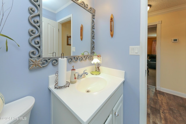 bathroom featuring toilet, crown molding, a textured ceiling, vanity, and hardwood / wood-style flooring