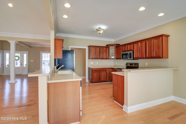 kitchen featuring kitchen peninsula, appliances with stainless steel finishes, light wood-type flooring, ornate columns, and sink