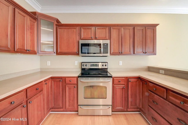 kitchen with appliances with stainless steel finishes, light wood-type flooring, and ornamental molding