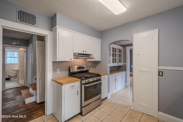 kitchen featuring white cabinets, light wood-type flooring, stainless steel range with gas cooktop, and wood counters