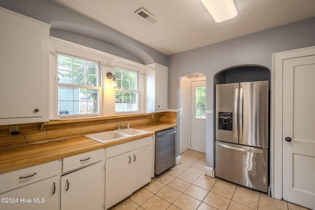 kitchen featuring white cabinets, appliances with stainless steel finishes, light tile patterned flooring, and sink