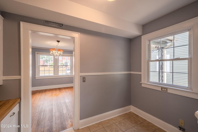 unfurnished room with light hardwood / wood-style floors, a chandelier, and ornamental molding