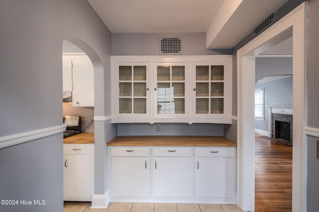 kitchen featuring light hardwood / wood-style flooring, wooden counters, and white cabinets