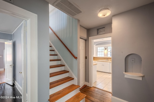 stairs with hardwood / wood-style flooring and sink