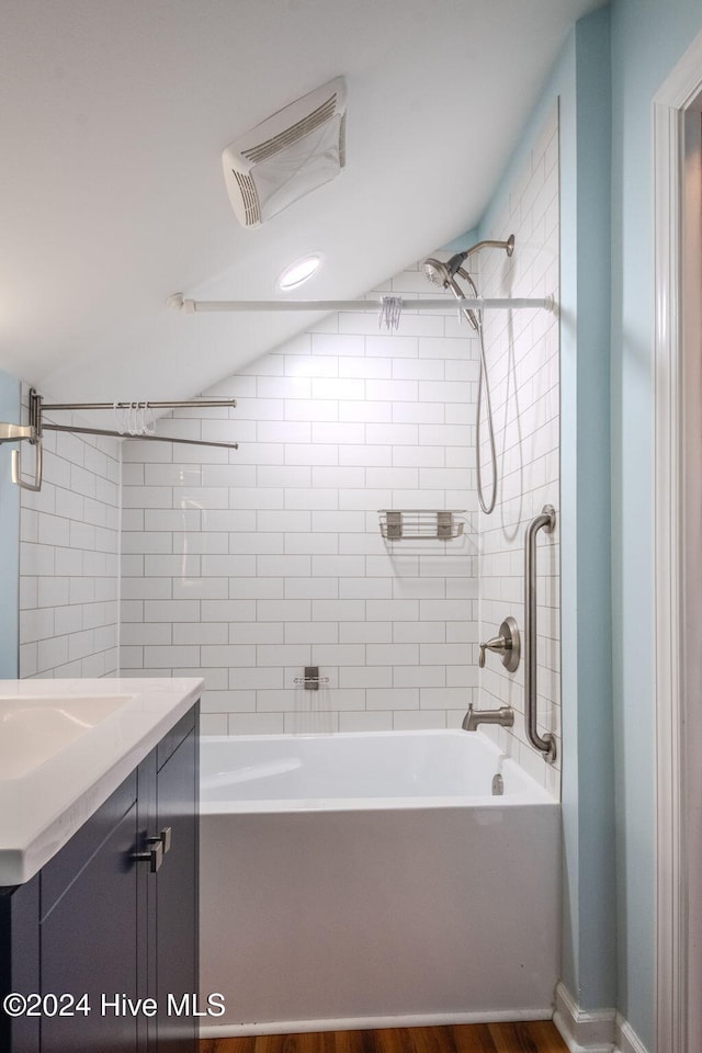 bathroom with hardwood / wood-style flooring, vanity, and tiled shower / bath