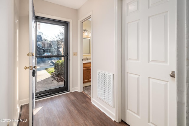 entryway featuring a sink, dark wood finished floors, visible vents, and baseboards