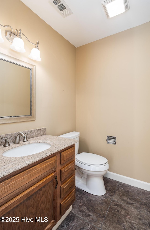 half bath with toilet, vanity, visible vents, and baseboards