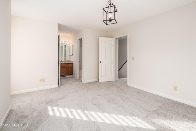 unfurnished bedroom featuring light carpet, connected bathroom, and baseboards