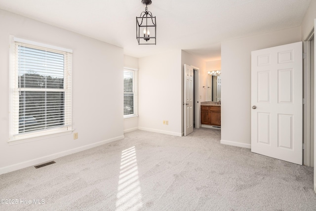 spare room with visible vents, a notable chandelier, light carpet, and baseboards