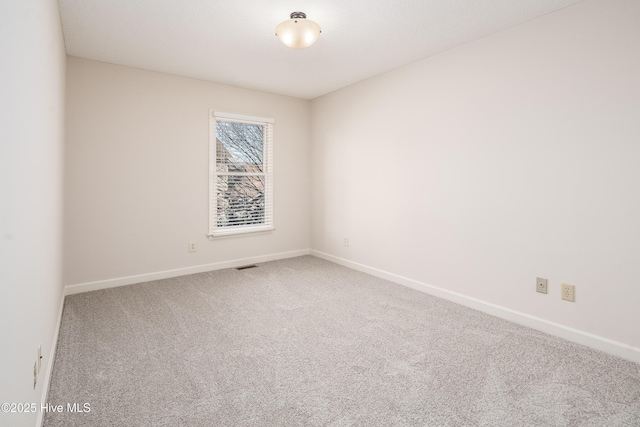 unfurnished room with carpet, visible vents, and baseboards