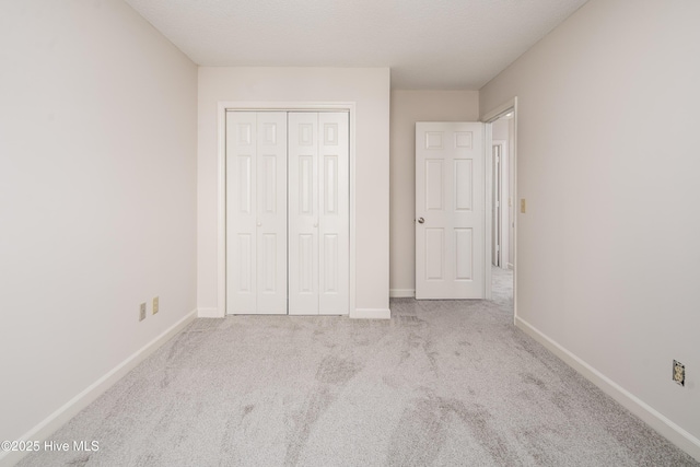 unfurnished bedroom with baseboards, a closet, and light colored carpet