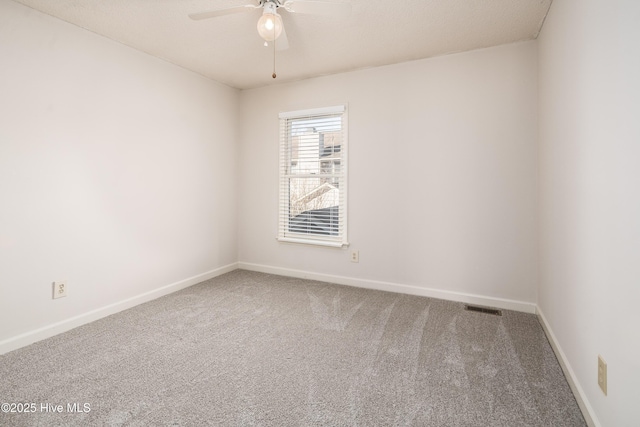 carpeted empty room featuring visible vents, ceiling fan, and baseboards