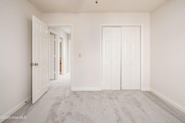 unfurnished bedroom with a closet, light carpet, and baseboards