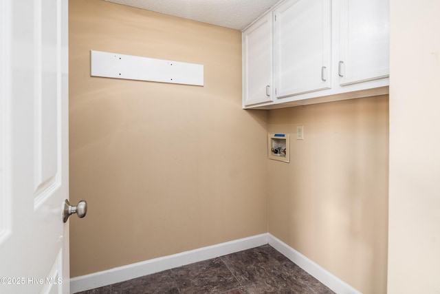 laundry area featuring a textured ceiling, hookup for a washing machine, cabinet space, and baseboards