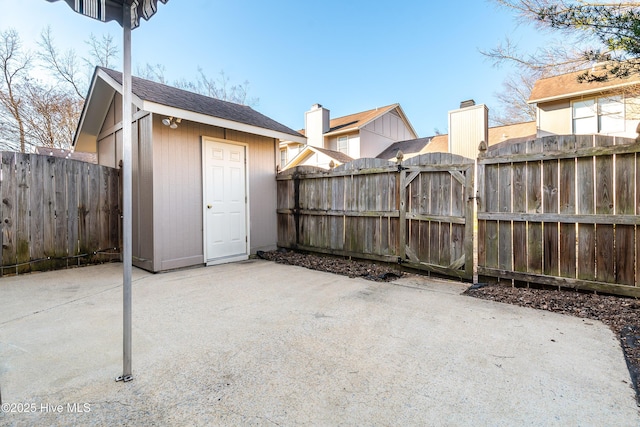 view of patio / terrace featuring a storage shed, a fenced backyard, a gate, and an outbuilding