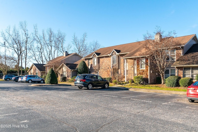 view of front of home with uncovered parking, a residential view, and brick siding