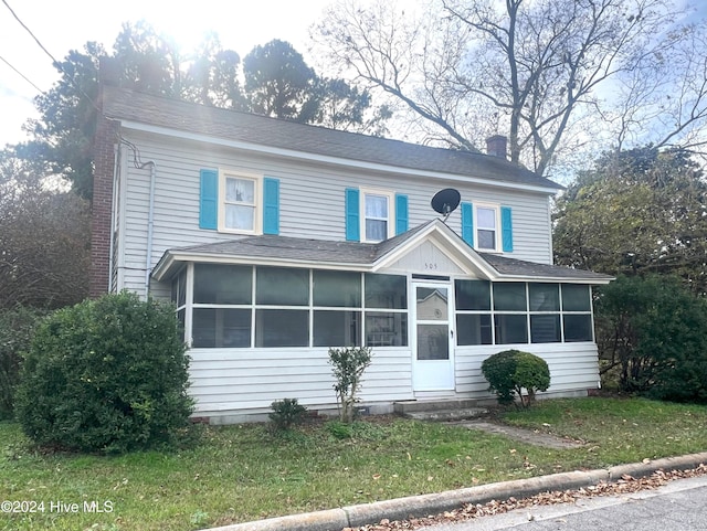 view of front of house with a front lawn and a sunroom