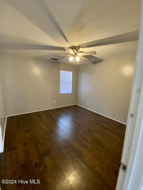 spare room with dark hardwood / wood-style flooring and ceiling fan