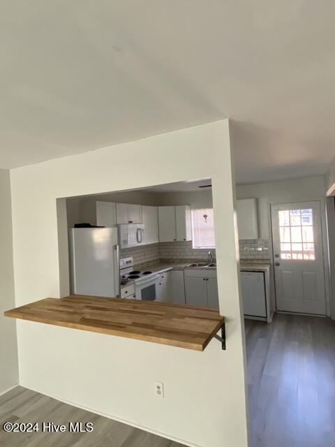 kitchen with wooden counters, kitchen peninsula, dark wood-type flooring, and white appliances