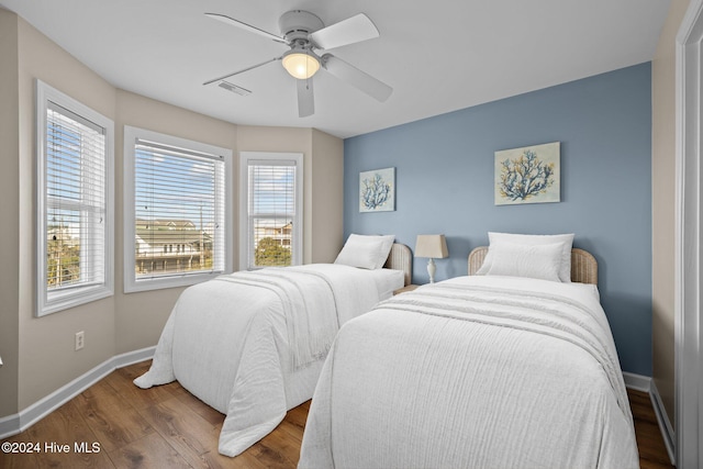 bedroom featuring ceiling fan, wood-type flooring, and multiple windows