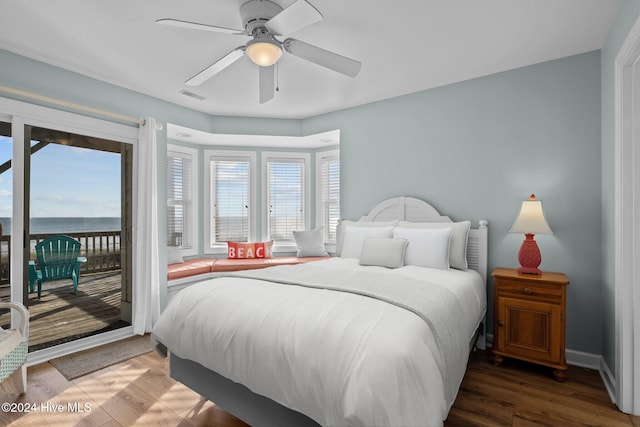 bedroom featuring a water view, hardwood / wood-style flooring, ceiling fan, and access to exterior