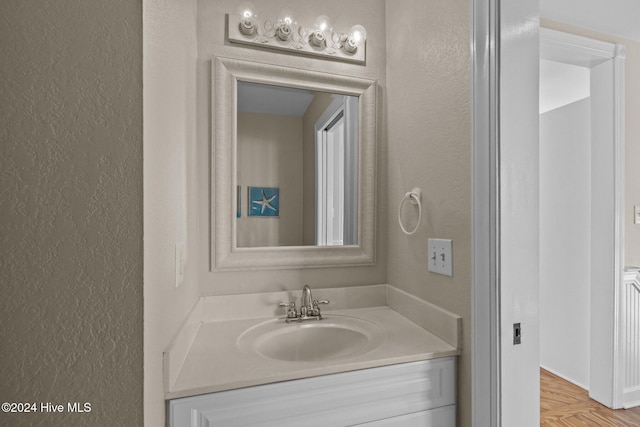 bathroom featuring parquet floors and vanity