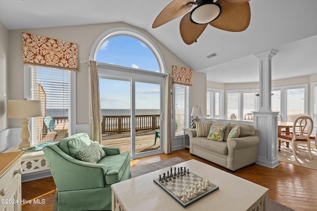 living room with a wealth of natural light, dark hardwood / wood-style floors, a water view, and vaulted ceiling