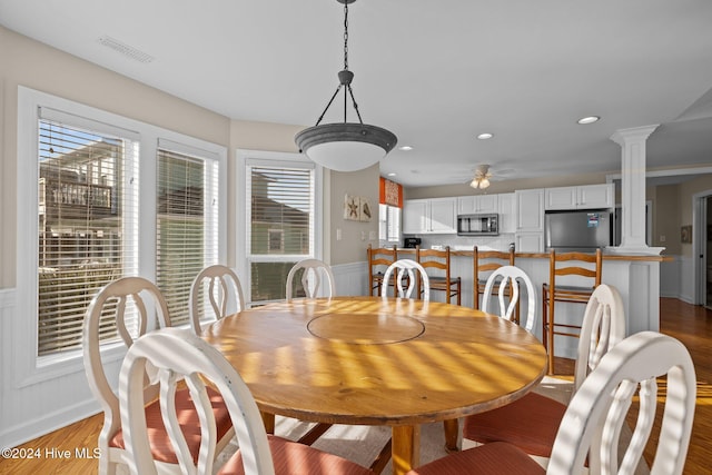 dining area featuring plenty of natural light, hardwood / wood-style flooring, ceiling fan, and decorative columns