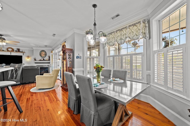 dining space with ceiling fan with notable chandelier, hardwood / wood-style flooring, and crown molding