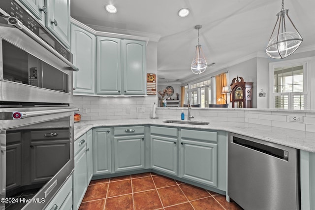 kitchen featuring stainless steel appliances, hanging light fixtures, sink, and tasteful backsplash