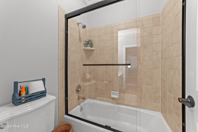 bathroom with toilet and shower / bath combination with glass door