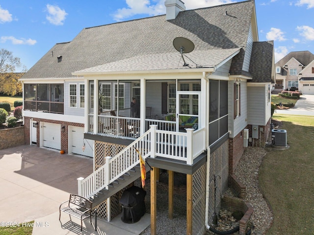 rear view of house with a garage, cooling unit, and a sunroom