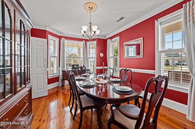 dining space featuring light wood-type flooring, a notable chandelier, and crown molding