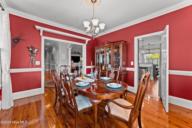 dining space featuring ornamental molding, hardwood / wood-style floors, and an inviting chandelier