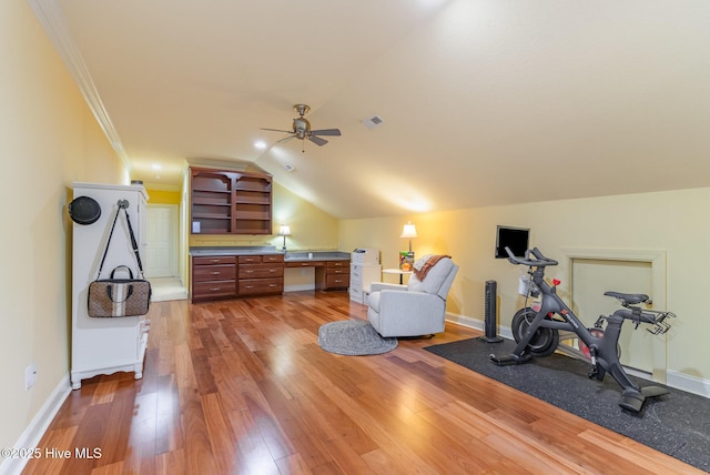 workout room featuring crown molding, hardwood / wood-style flooring, ceiling fan, built in desk, and vaulted ceiling