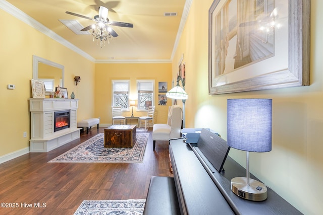 living room with dark wood-type flooring, ceiling fan, and ornamental molding