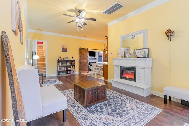 living room with ornamental molding, a barn door, dark hardwood / wood-style floors, and ceiling fan